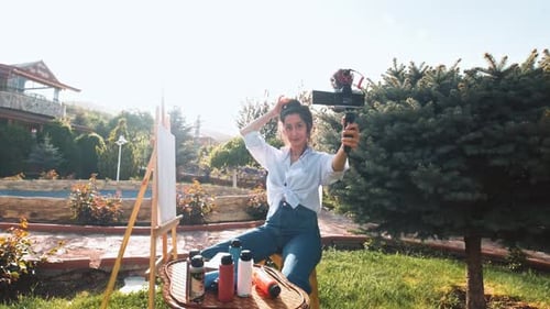 Woman Recording Herself Painting on Easel Outdoors