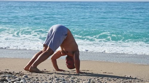 Young Man Doing the Pushups on the Beach