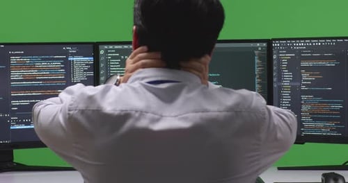 Back View Developer Having Headache While Write Code With Multiple Computer Screens In Green Screen