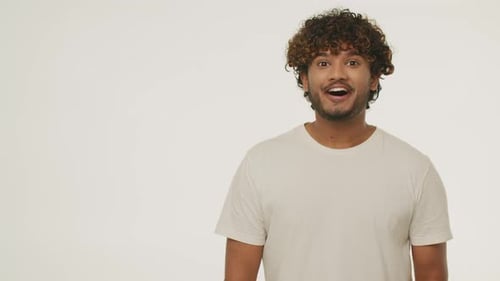 Smiling Young Man Pointing to the Side with Finger and Showing Thumbs Up Studio Footage of Excited