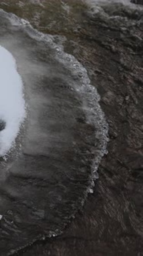 Water In The Stream Flowing Through The Ice Melting In The Shoreline
