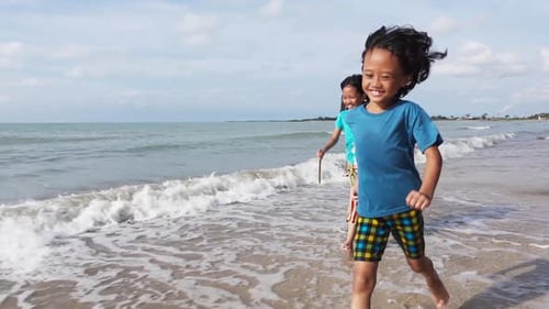 Two little girls running joyfully along the beach in slow motion