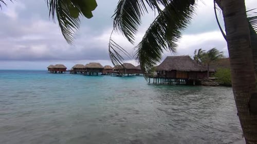 Beautiful Bora Bora lagoon with over water bungalows framed with palm trees on a stormy day