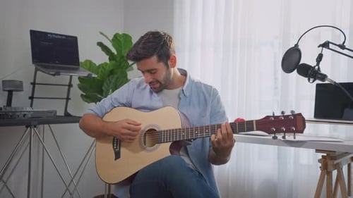 Young Adult Man Playing Acoustic Guitar Indoors