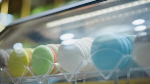 CloseUp of Colorful Macarons Displayed in Glass Case with Reflective Lighting