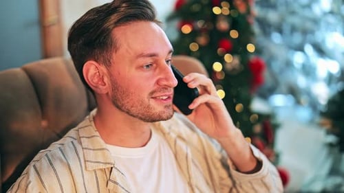 Smiling man talking on phone near Christmas tree