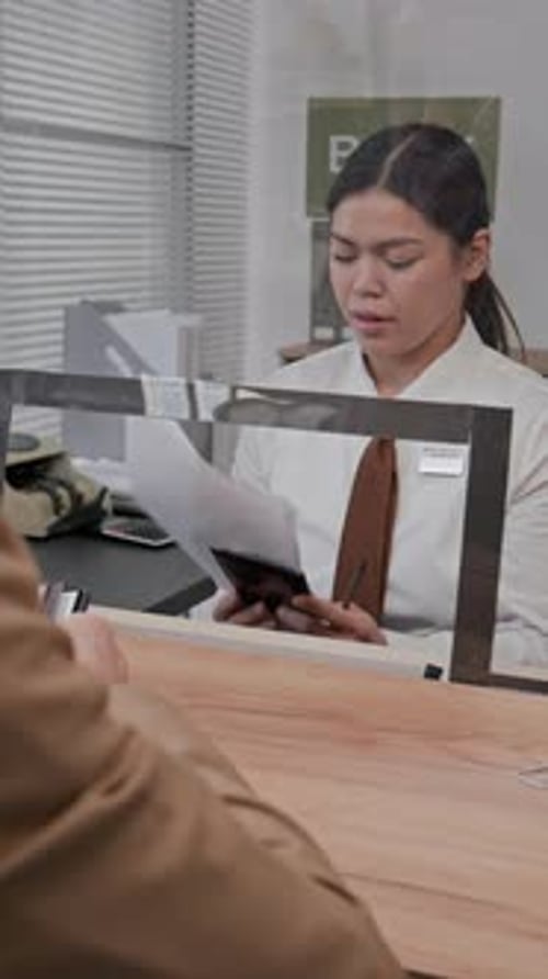 Friendly Woman Bank Teller Assists Customer With Paperwork