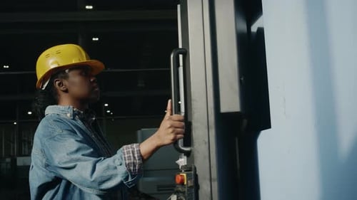 Female Factory Worker Operating Industrial Machine