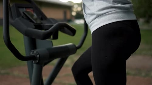 Woman Enjoying Outdoor Workout on Fitness Equipment in Park During Cloudy Afternoon