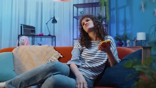 Frustrated Woman Using Phone on Couch at Night