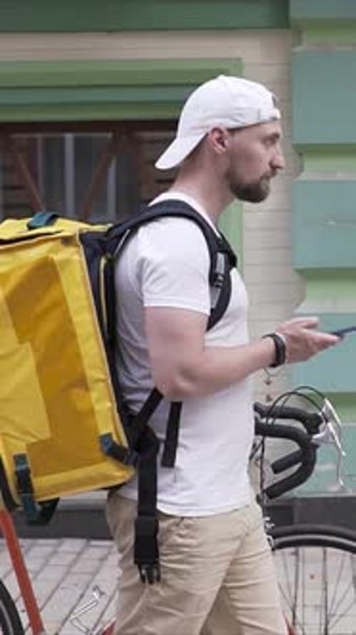 Man Using Phone with Bicycle and Delivery Backpack