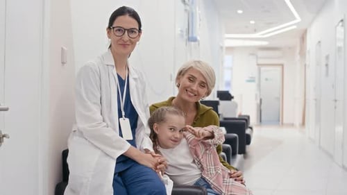 Portrait of Pediatrician Sitting next to Mother and Daughter in Clinic Hall