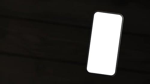 The mobile phone is slightly raised above the wooden table, showing a white screen.