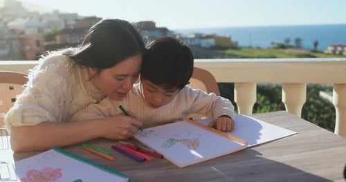 Mother and Child Drawing Together on Sunny Balcony