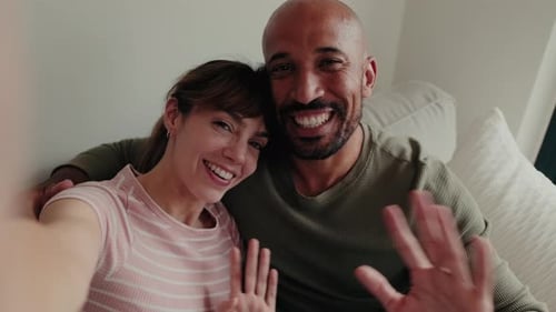 Couple Smiling and Waving into Camera on Couch