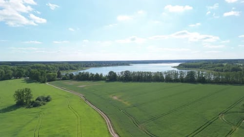 An aerial view of a picturesque countryside landscape. The footage captures a serene lake, lush gree