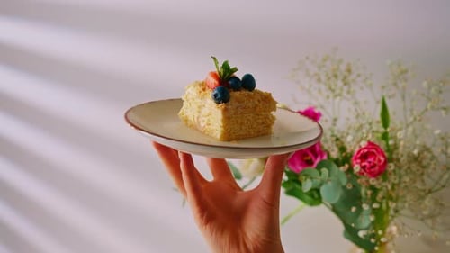 slice of freshly made delicious puff pastry Napoleon cake with strawberries and berries in a plate