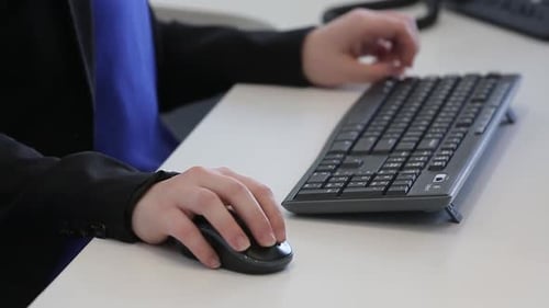 Tight shot of woman preparing to use a mouse and keyboard at a computer.