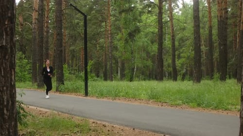 Athlete Runs Through Pine Forest Black Gear Blending with Nature Phytoncides Boost Immunity Jogging