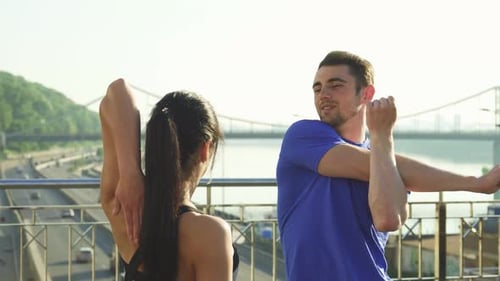 Energetic Young Couple Stretching Together in the Morning Sun
