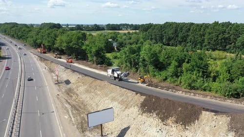 Roadworks of a new asphalt road. Modern machinery working on a road construction in summertime.