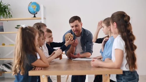 Showing the wooden puzzle. Group of children students in class at school with teacher