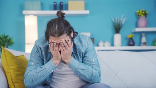 Stressed Man Rubbing Face While Sitting on Couch