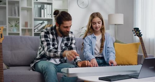 Girl and Adult Playing Piano Together at Home