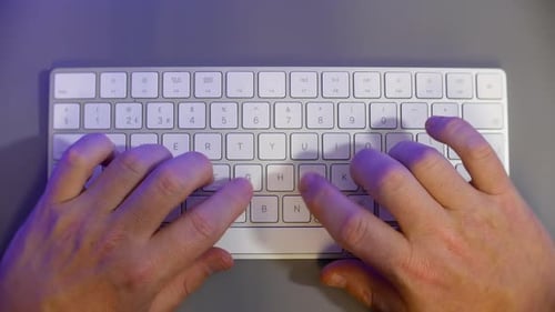 Fingers typing on computer keyboard overhead