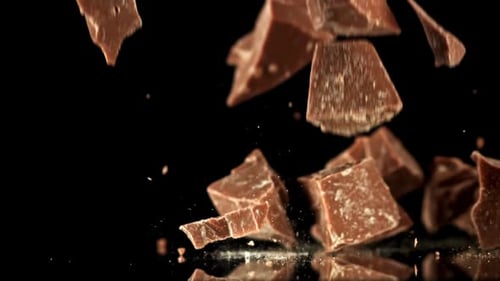 Chocolate chunks falling in slow motion on black
