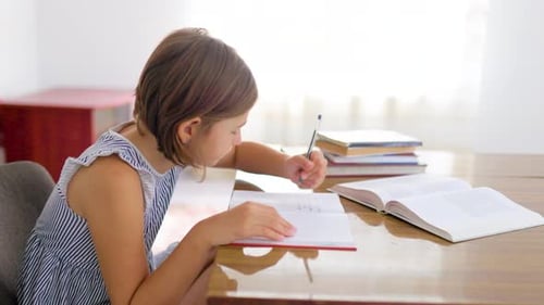 Side View School Child Girl Carefully Concentrate Write in Notebook While Sitting at Table