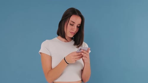 Surprise, happiness and winner, excited girl with cellphone isolated on blue background in studio