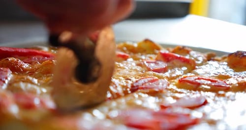 Chef Slicing a Pepperoni Pizza Into Multiple Slices with a Pizza Cutter. Slow Motion Close-up