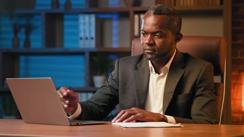 Serious Man Signing Documents at Desk at Night