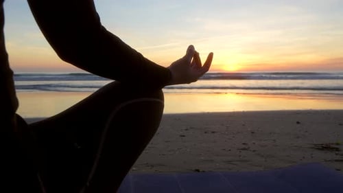 mantra with the hand of a woman who is doing yoga in front of the sea