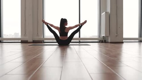 Woman Stretches in Bright Studio with City View