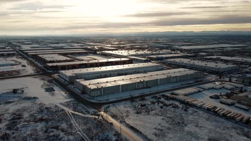 Giant warehouses covered with snow in the middle of winter with the Rocky Mountains in the backgroun