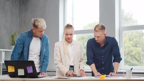 Team of Young Startupers is Working at the Table in the Office Discussing the Strategy and