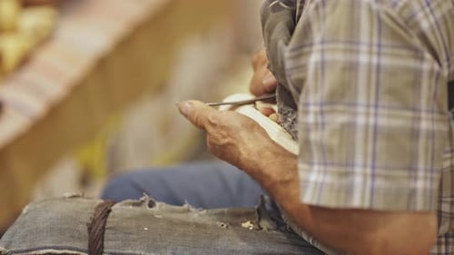 Adult Woodworker Carefully Carving Wood with Blade
