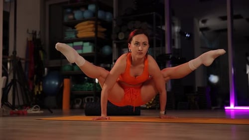 Flexible Frau führt Yoga-Übung in Glühwürmchen-Pose durch