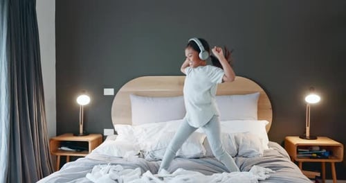 Happy Girl Dancing on Bed with Headphones On