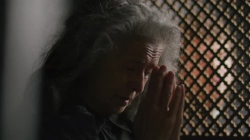 Senior Woman Listening to Priest and Praying in Confessional Booth