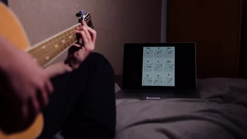 Teen Practices Guitar with Online Lesson at Night