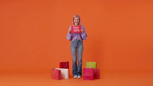 Excited Woman with Sale Sign Surrounded by Shopping Bags