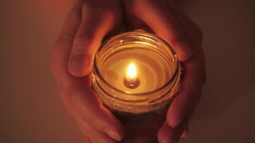 Manos sosteniendo una vela encendida de cerca