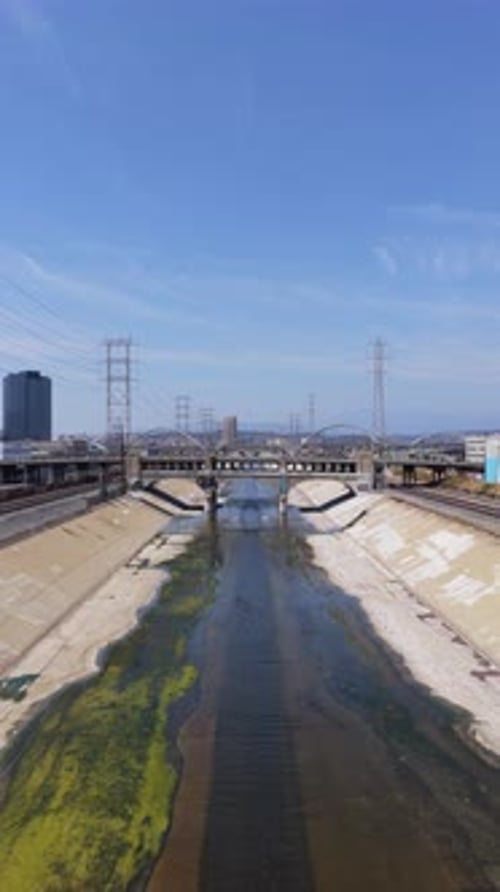 Viaduct Bridge Crossing Los Angeles River with Power Lines Railroad Tracks and Cityscape Against
