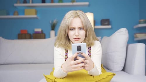 Worried Young Woman Using Smartphone at Home