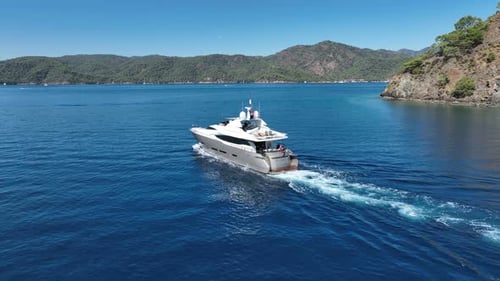 A luxury yacht cruising on a calm, blue sea on a sunny day.