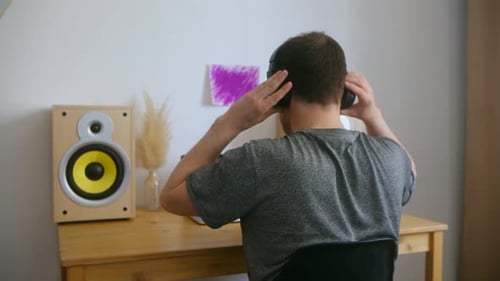 A Man in a Home Music Studio Sits at a Desk with Equipment and Stuck Using the Laptop