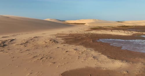Golden Hour Desert Landscape with Water Patches - Aerial Flyover